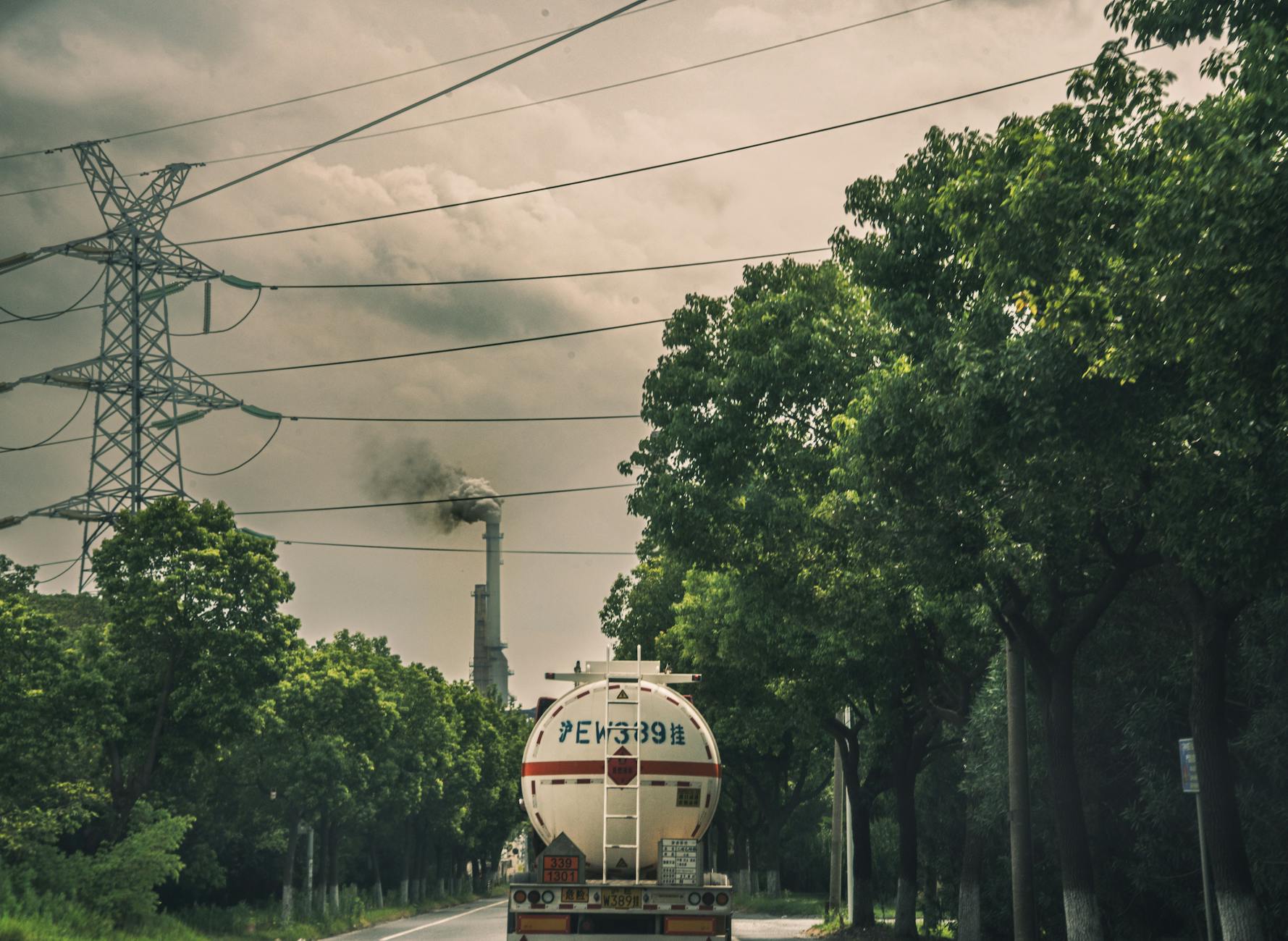 Cysterna ADR na drodze obok komina przemysłowego i linii wysokiego napięcia