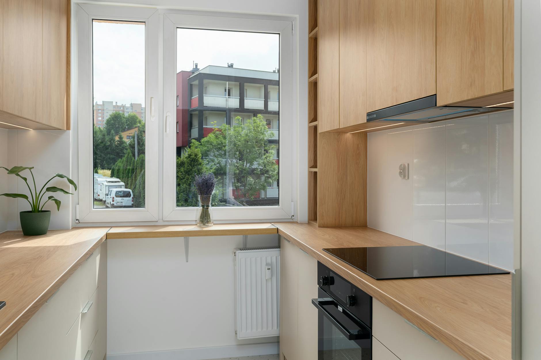 Mała kuchnia w bloku z drewnianymi szafkami i widokiem na Kraków
