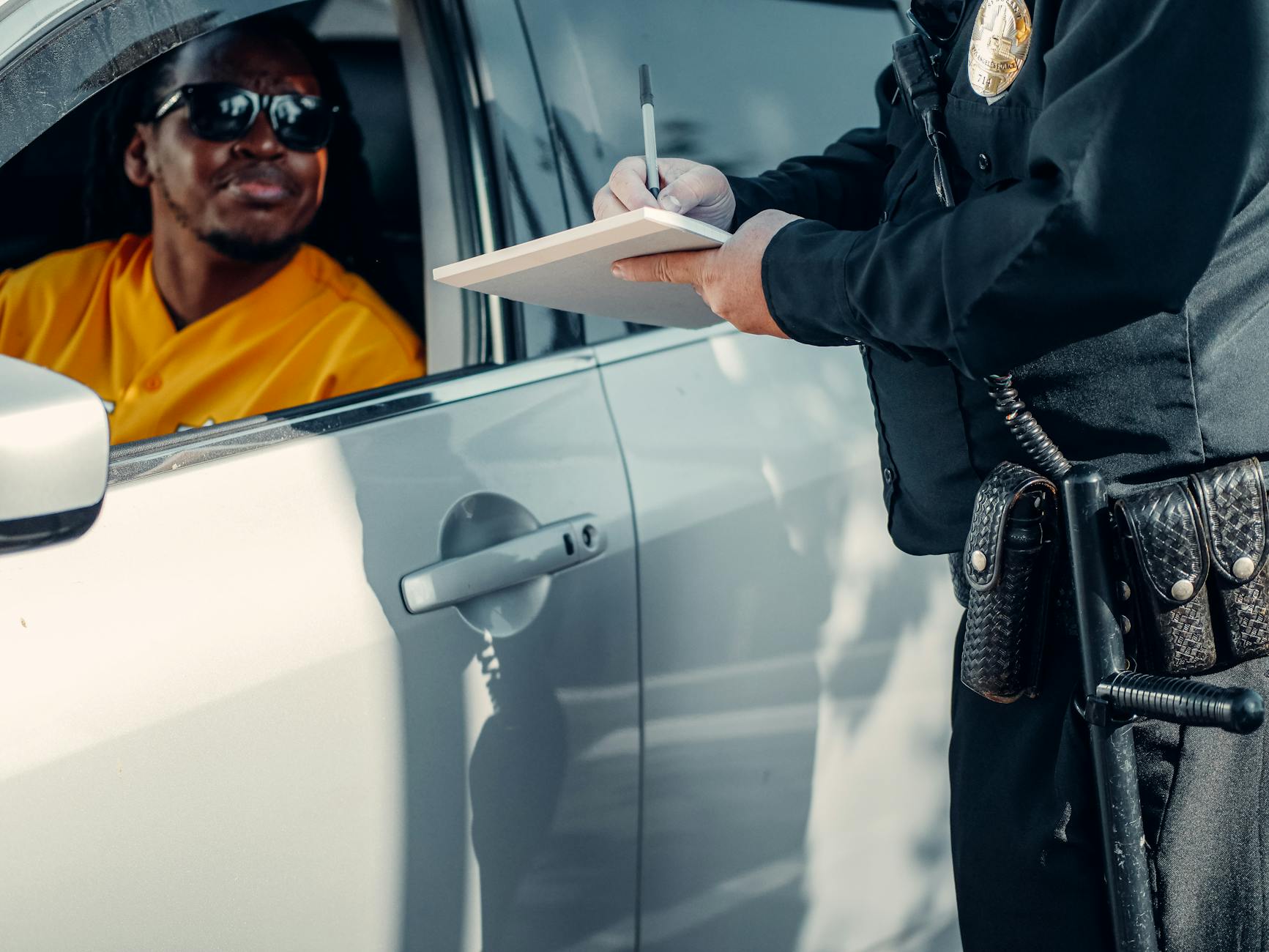 Policjant drogówki wypisuje mandat kierowcy zatrzymanemu do kontroli