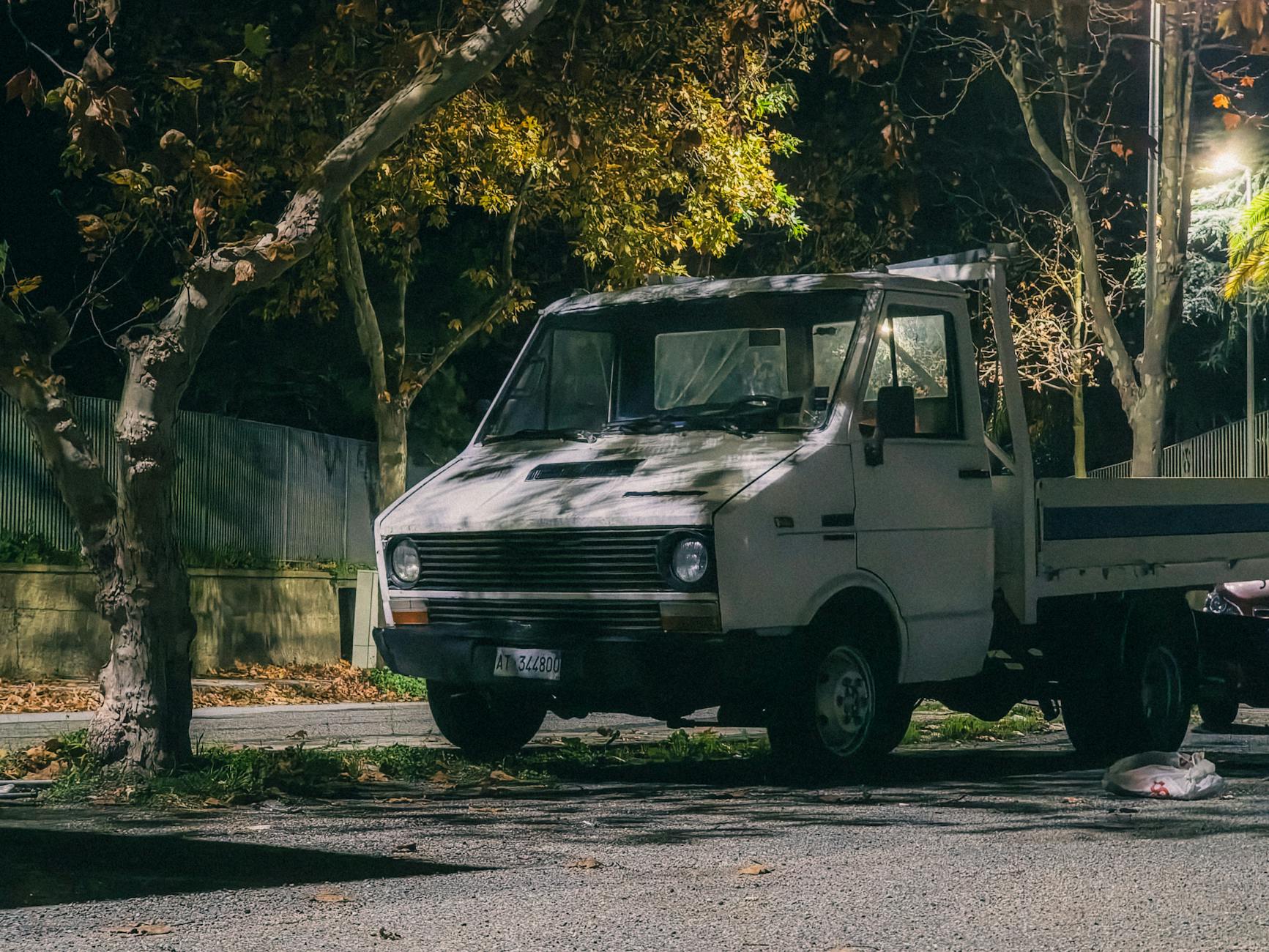 Ciężarówka zaparkowana nocą pod latarniami wśród jesiennych drzew