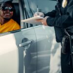 Policjant wypisuje mandat kierowcy zatrzymanemu do kontroli drogowej