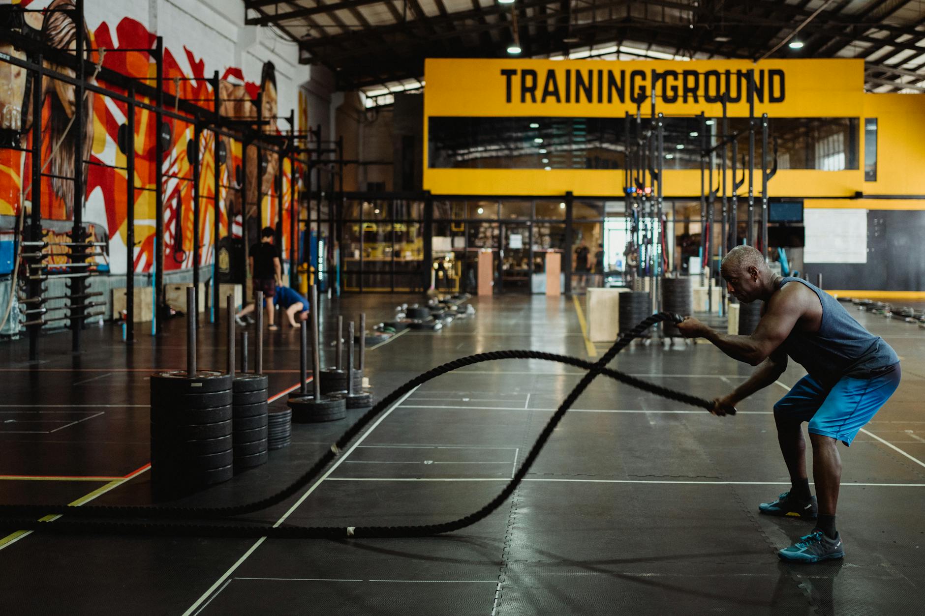 Mężczyzna ćwiczy z linami battle ropes w przestronnej siłowni