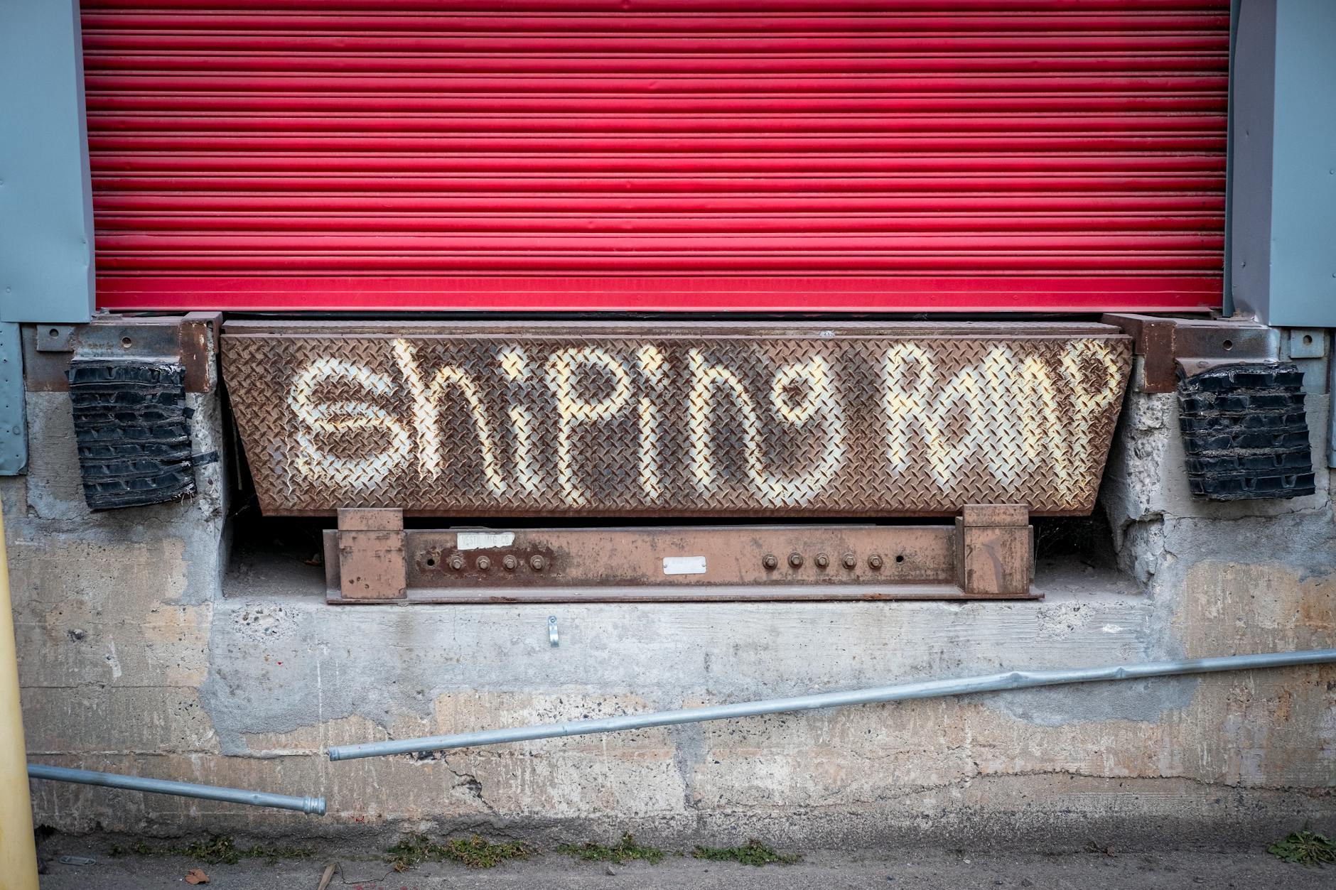Rampa załadunkowa z czerwonymi bramami i betonową ścianą z graffiti