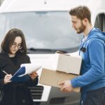 Protokół zdawczo odbiorczy maszyn: jakie punkty zabezpieczają obie strony Kurier wręcza paczki kobiecie podpisującej dokumenty przy samochodzie dostawczym
