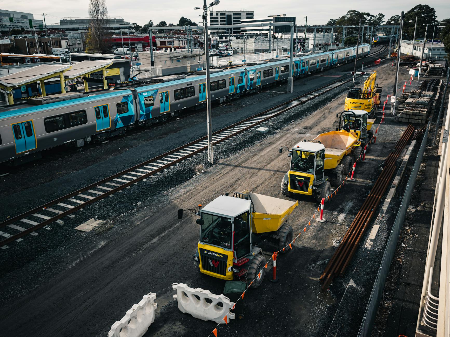 Planowanie trasy przy relokacji maszyn: dojazd, wjazd na teren i miejsce rozładunku Pojazdy budowlane przy torach kolejowych obok stacji pasażerskiej